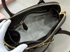 MiuMiu handbag open with dark fabric lining and gold zipper, dark brown