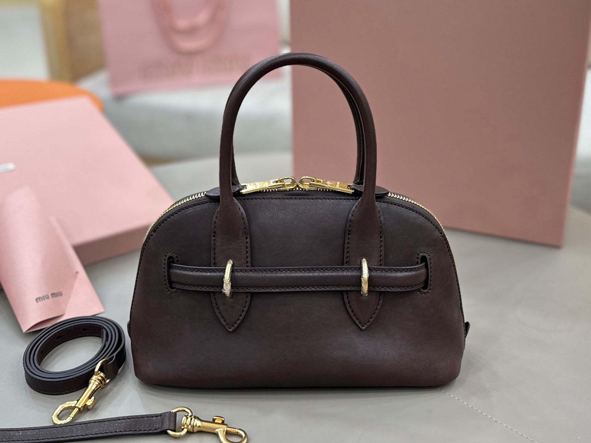 MiuMiu handbag with top handles, front belt detail, and gold-tone hardware, dark brown