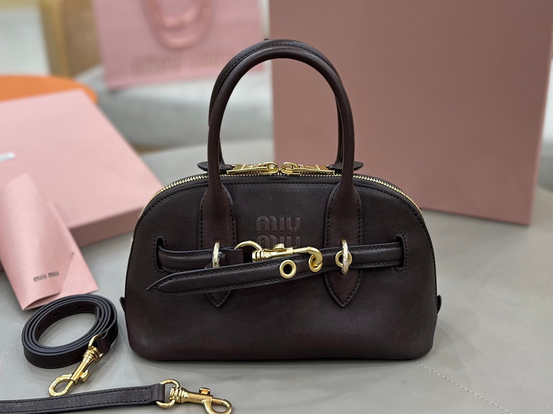 MiuMiu handbag with top handles, front flap, and gold-tone hardware, dark brown