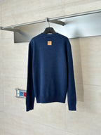 Back of navy knit sweater with small square logo patch at upper back