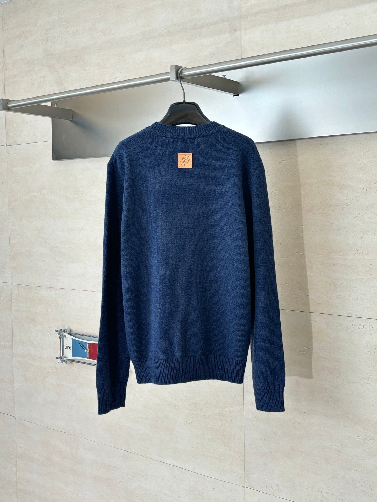 Back of navy knit sweater with small square logo patch at upper back