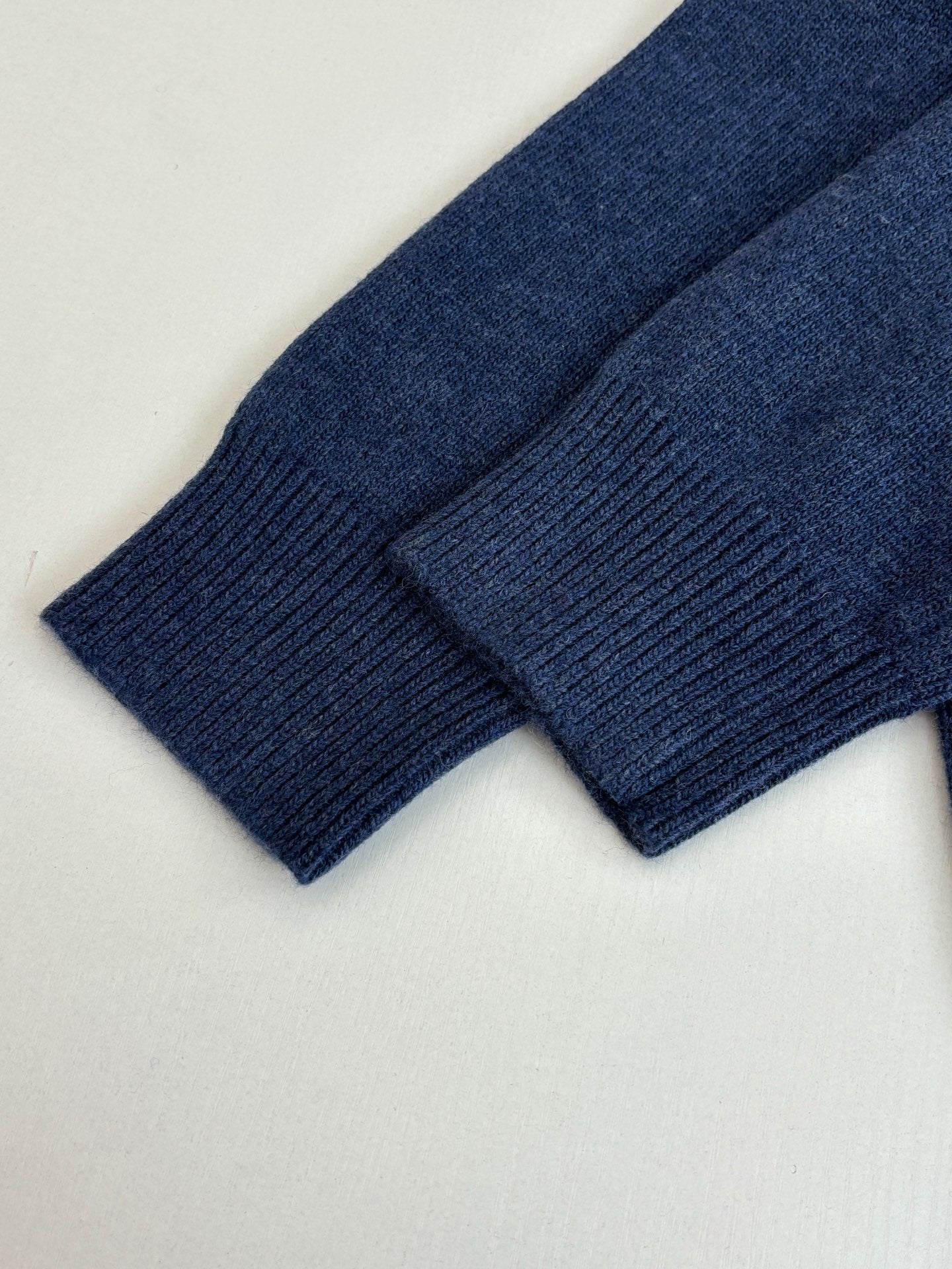 Navy ribbed knit sleeves and cuffs laid flat, sweater texture close-up