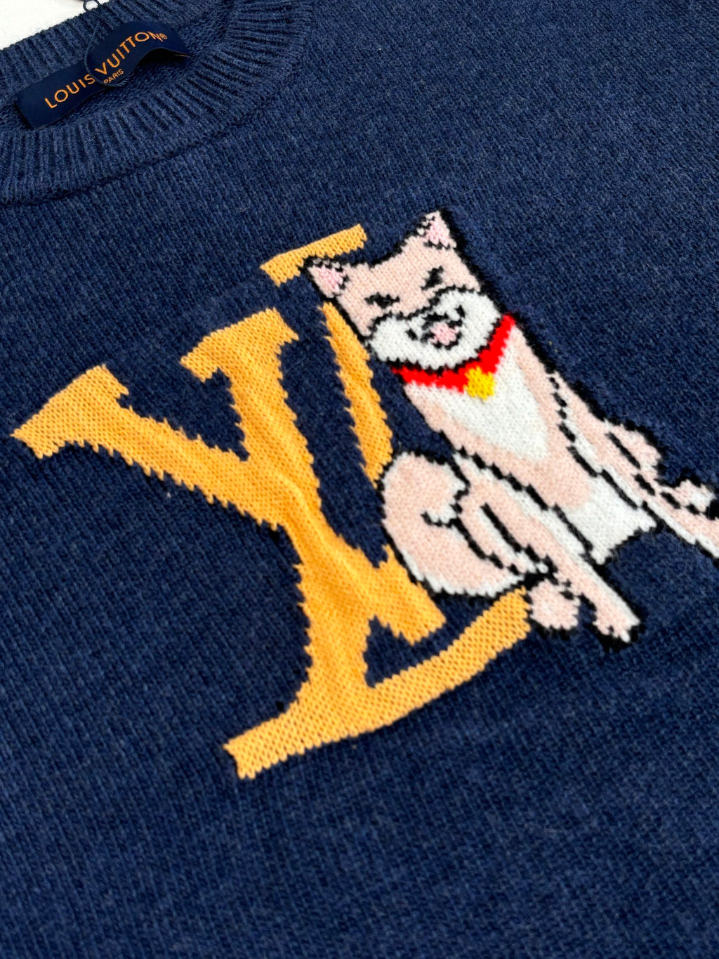 Close-up of navy knit sweater with multicolor cat graphic and yellow LV letters