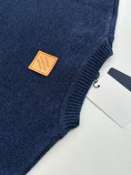 Navy knit sweater with tan brand label patch near side seam and small tag