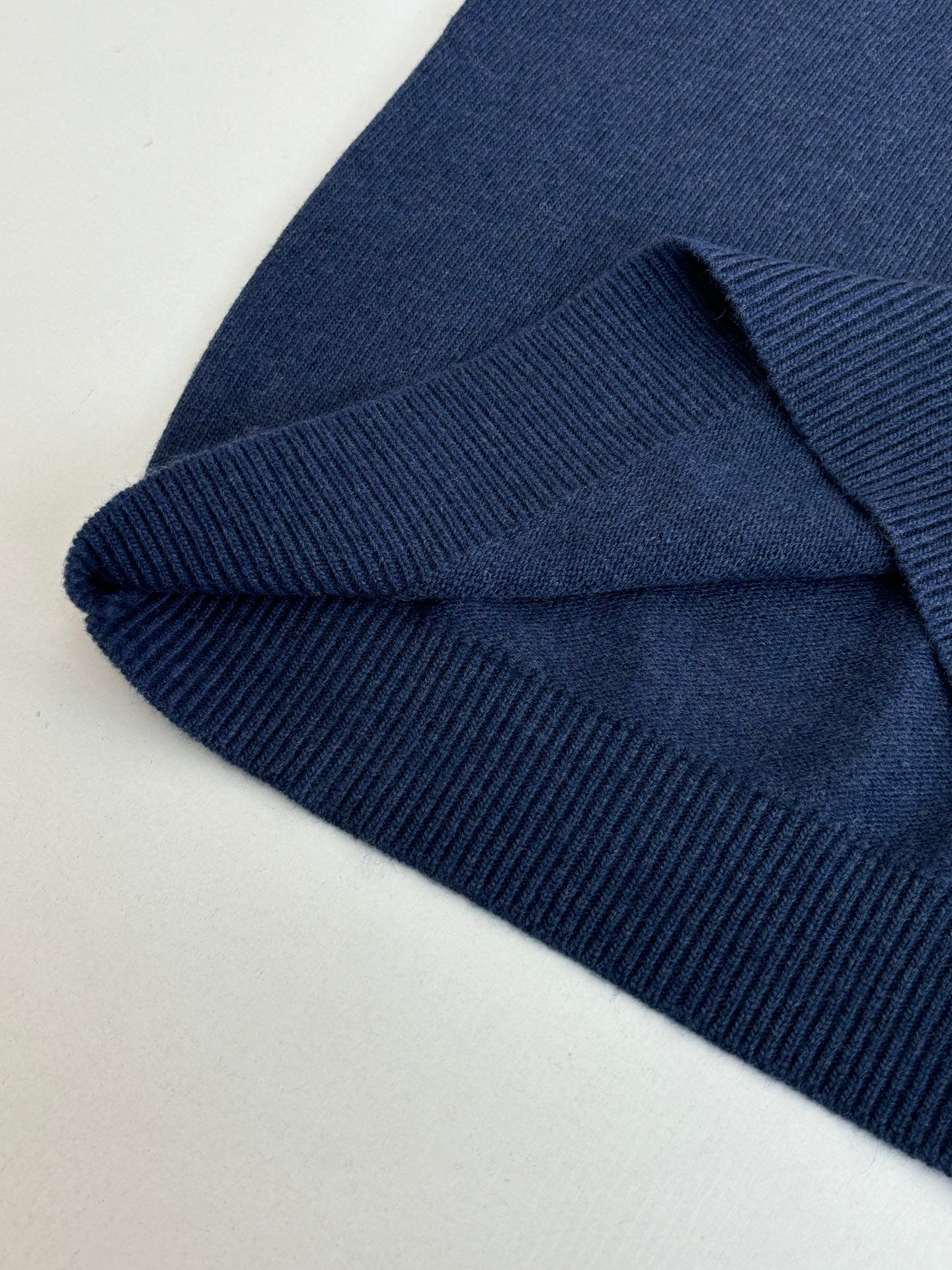Folded navy sweater hem with ribbed knit cuff texture detail