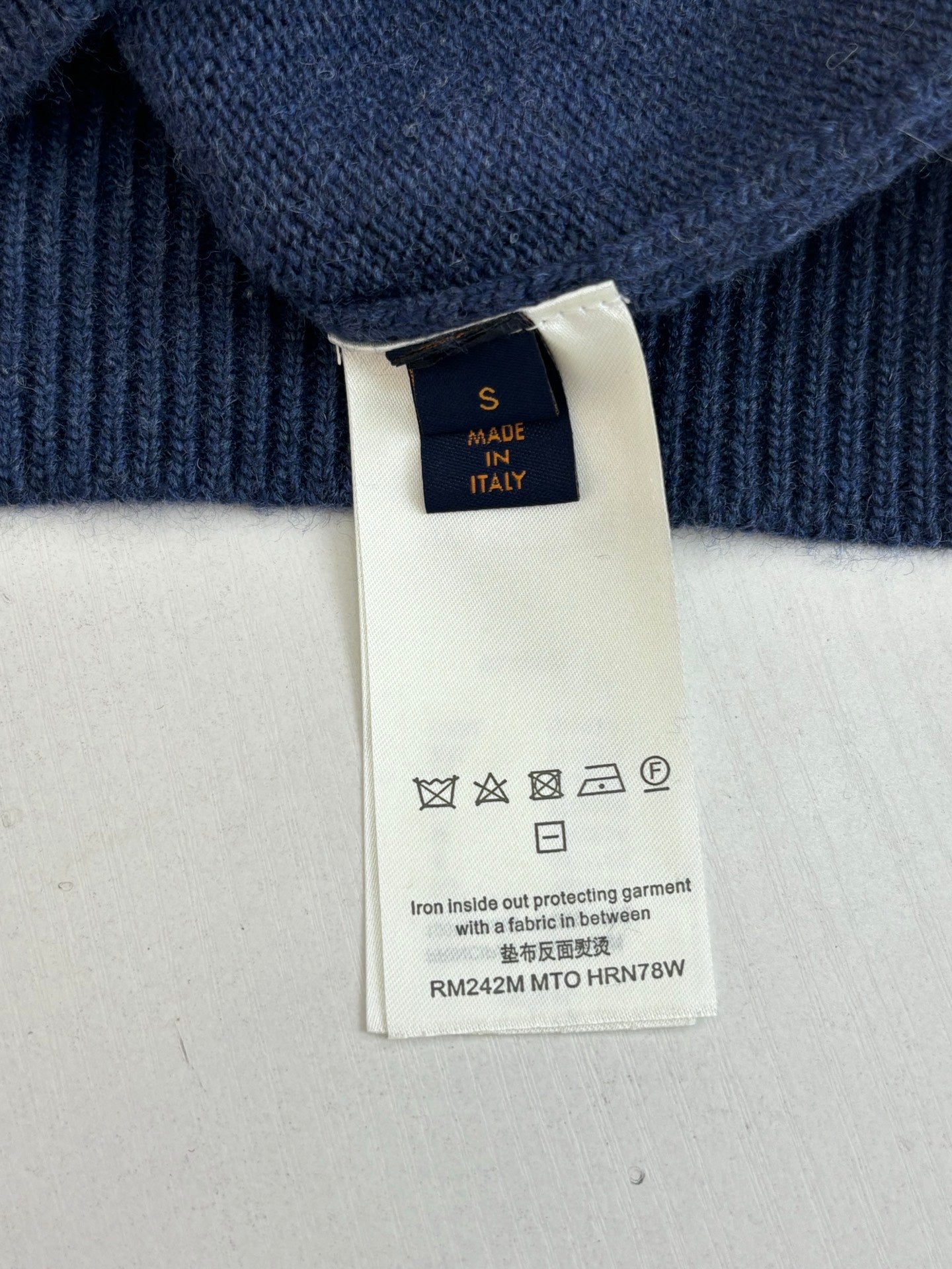 Navy sweater care label tag showing made in Italy and washing symbols
