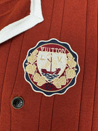 Red knit cardigan close-up with crest patch and round button