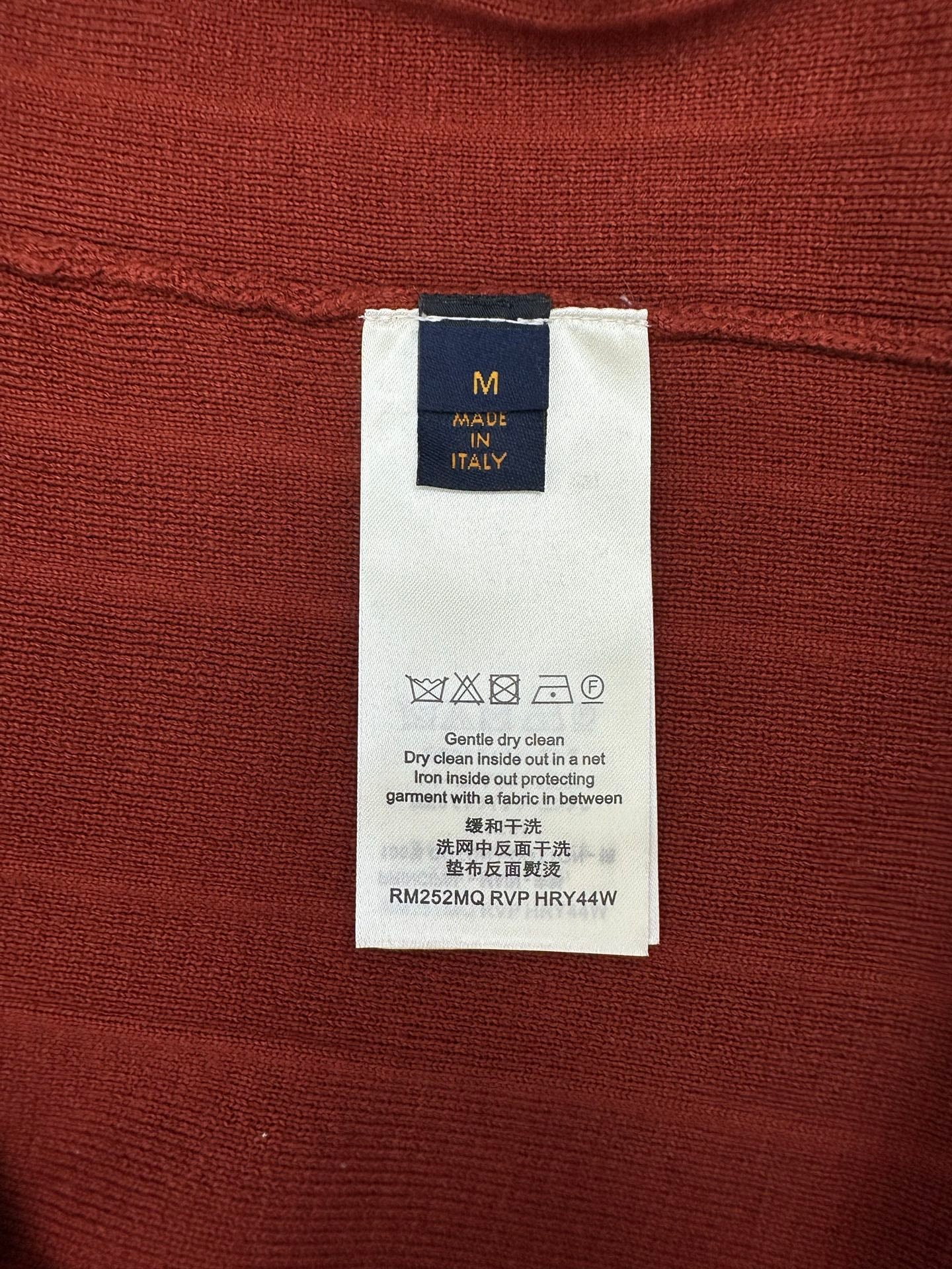 Red knit cardigan care label tag with size M and washing icons