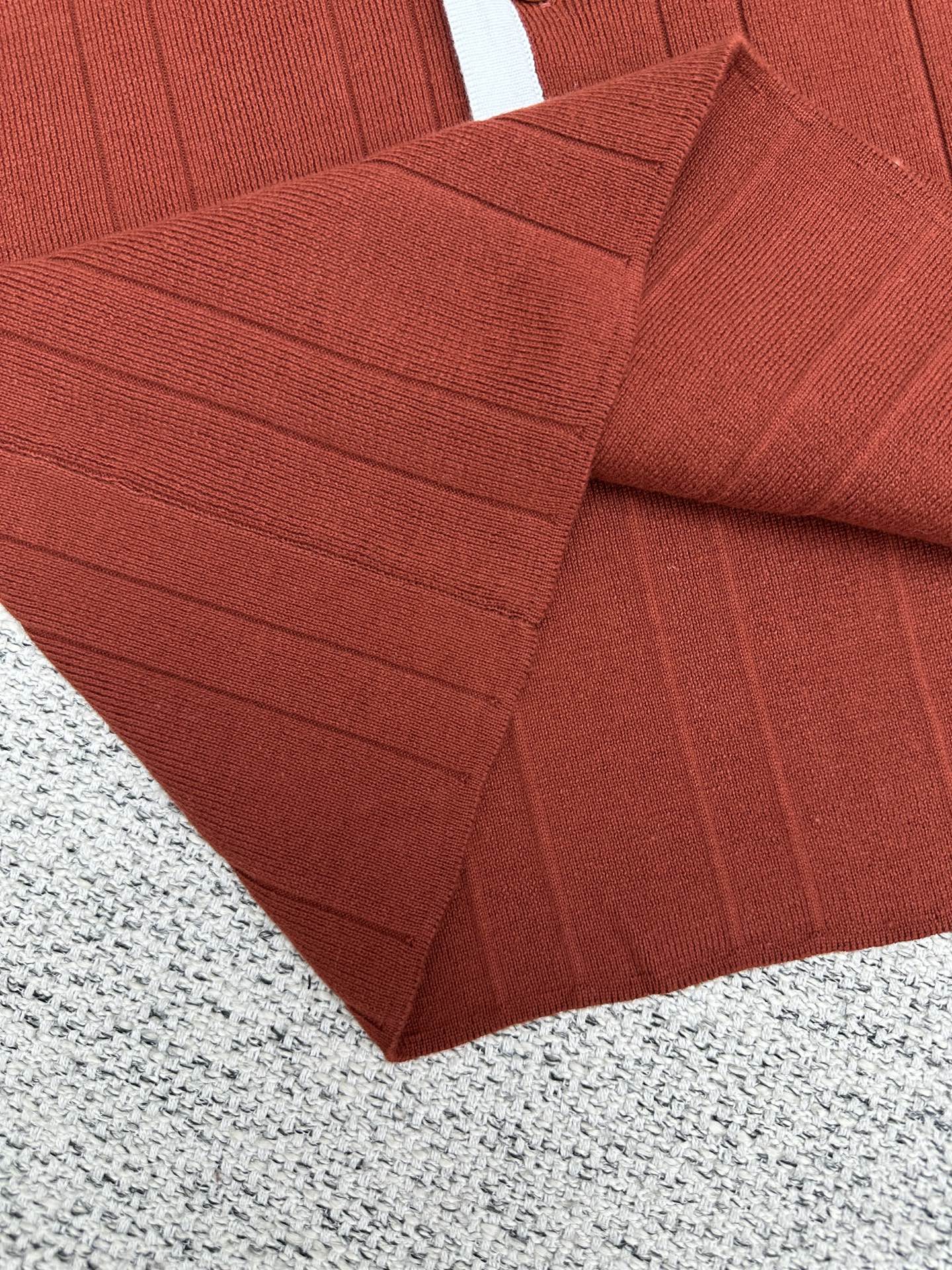 Red knit cardigan sleeve with textured ribbing and stitched seam detail