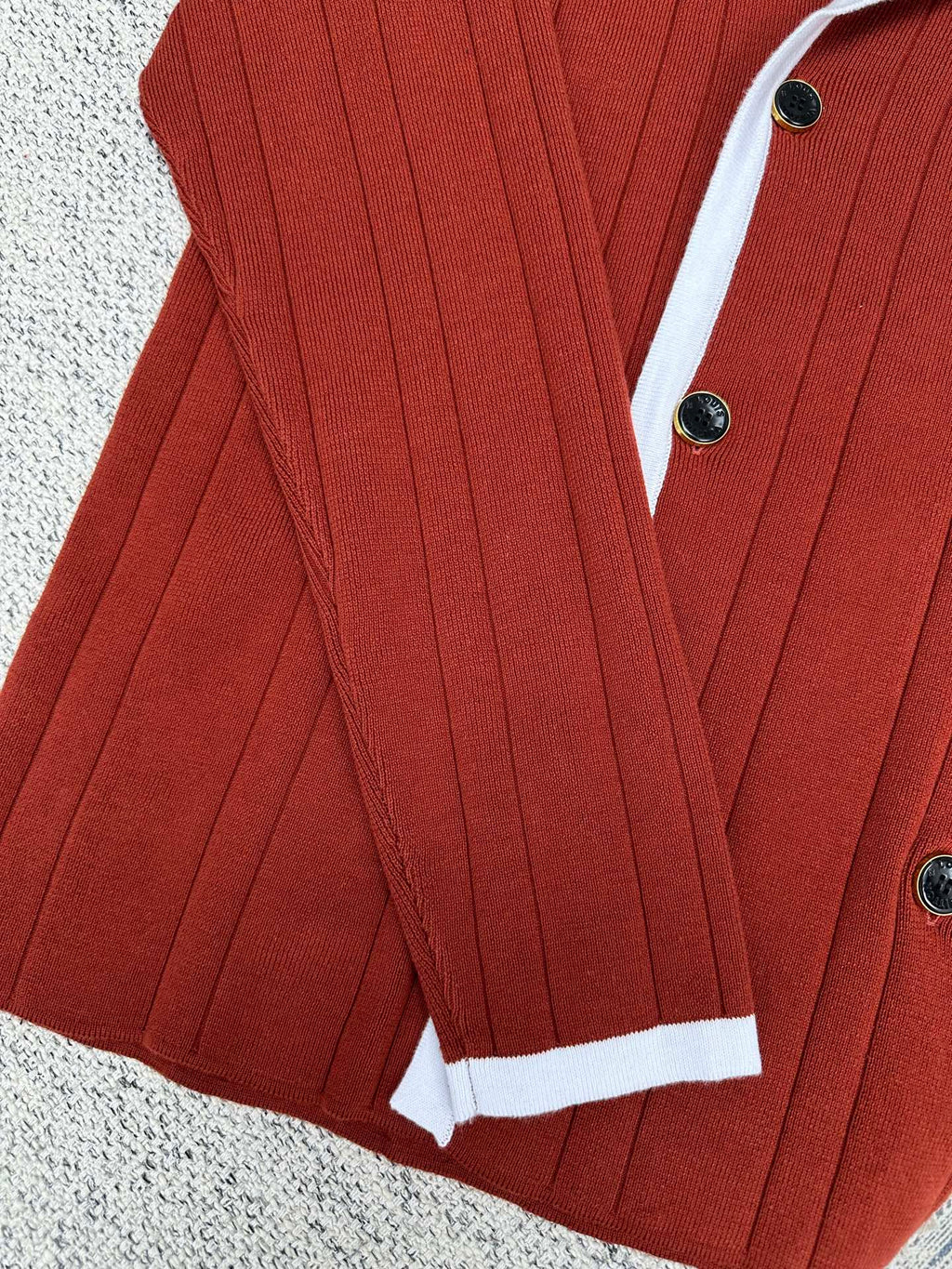 Red knit cardigan with white cuffs, button front, and vertical rib texture