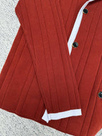 Red knit cardigan with white cuffs, button front, and vertical rib texture