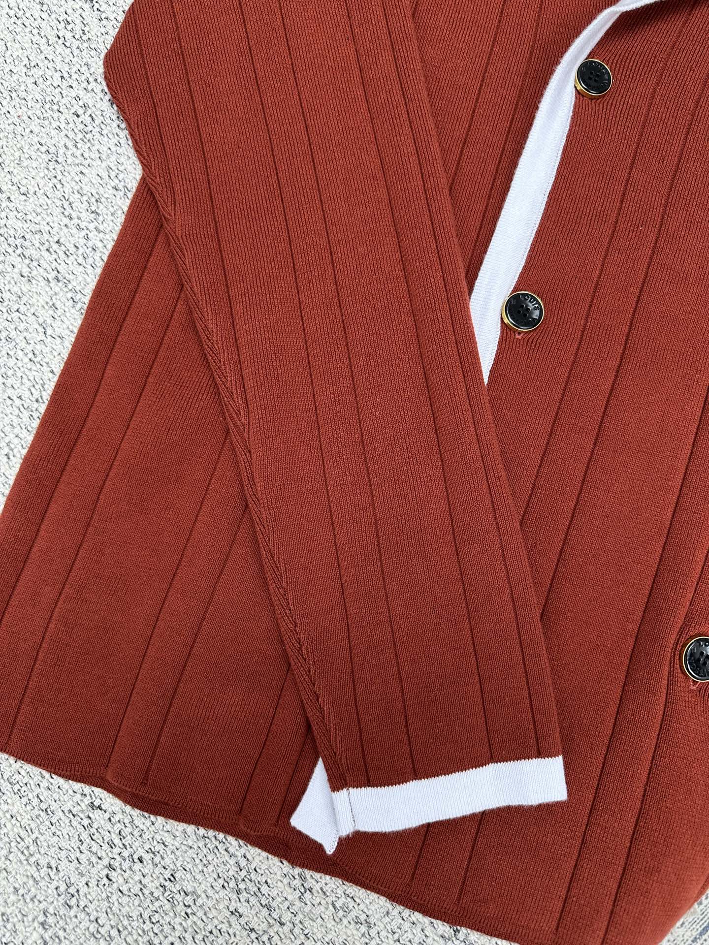 Red knit cardigan with white cuffs, button front, and vertical rib texture
