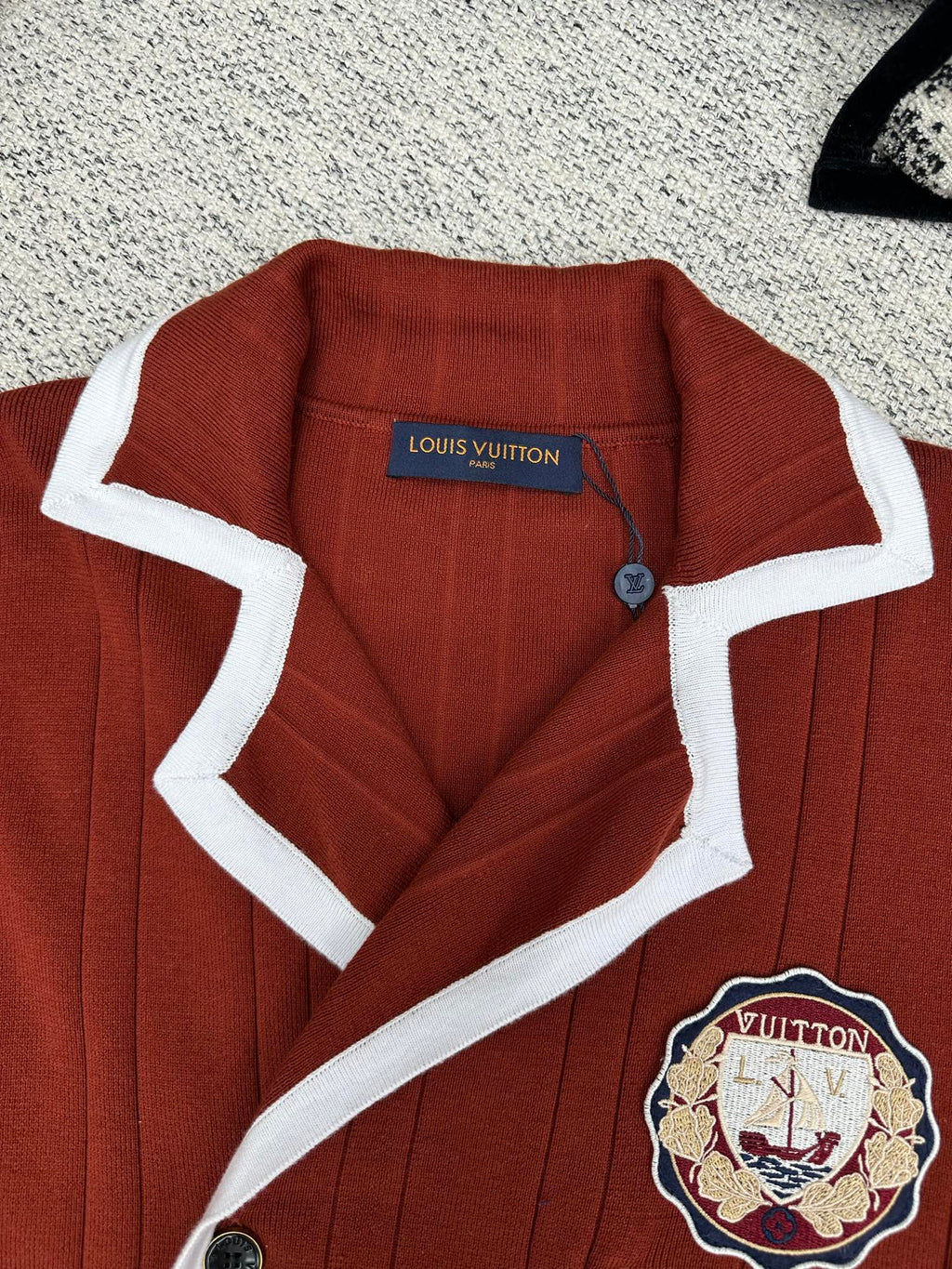 Red knit cardigan with white-trim collar, button placket, crest patch