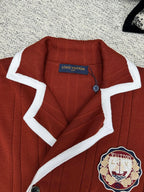Red knit cardigan with white-trim collar, button placket, crest patch
