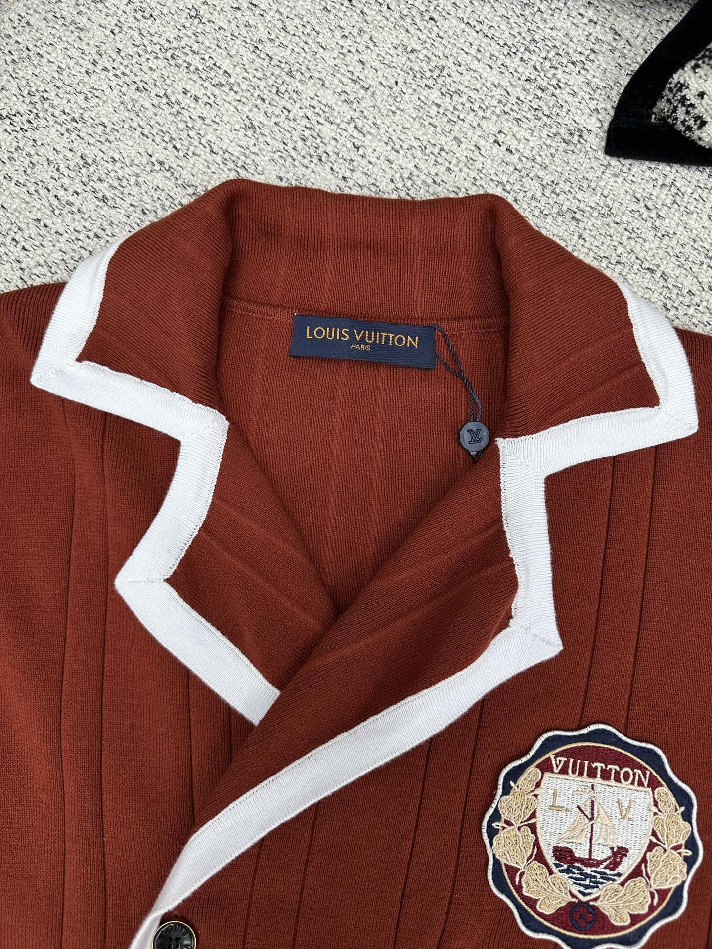 Red knit cardigan with white-trim collar, button placket, crest patch