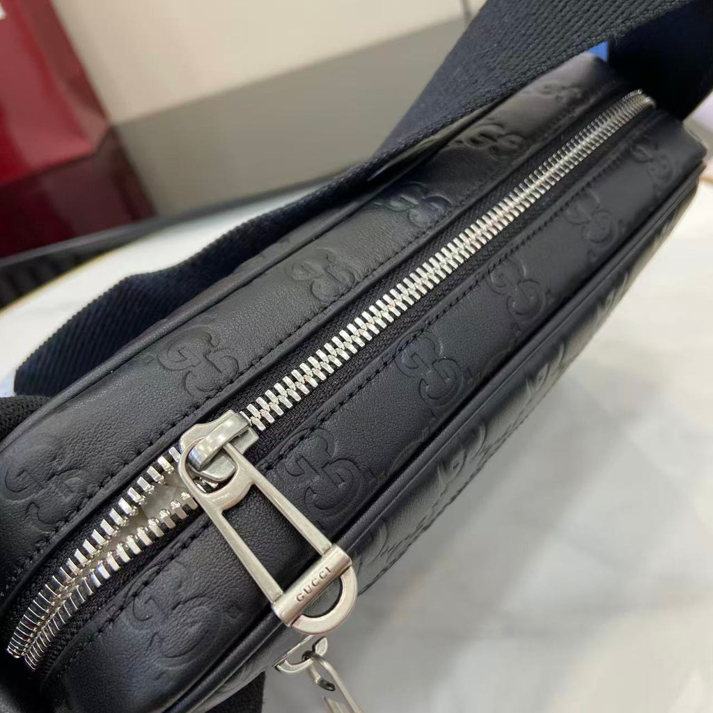Gucci bag close-up: dark blue embossed GG leather with silver zipper and ring pull