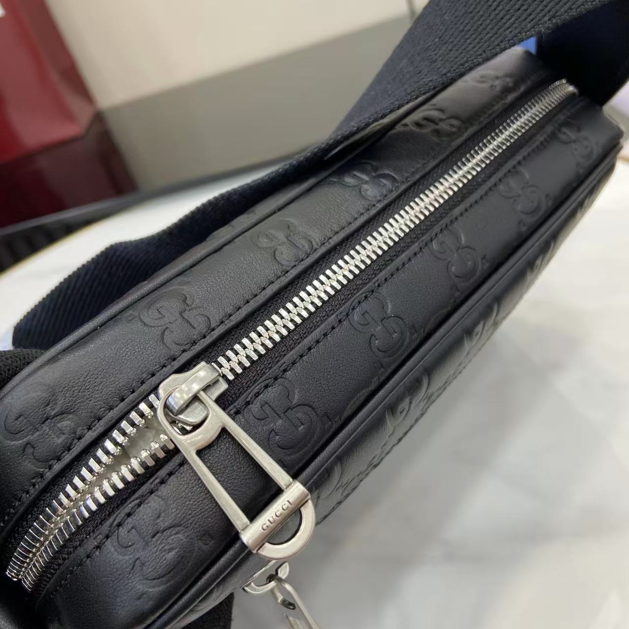 Gucci bag close-up: dark blue embossed GG leather with silver zipper and ring pull
