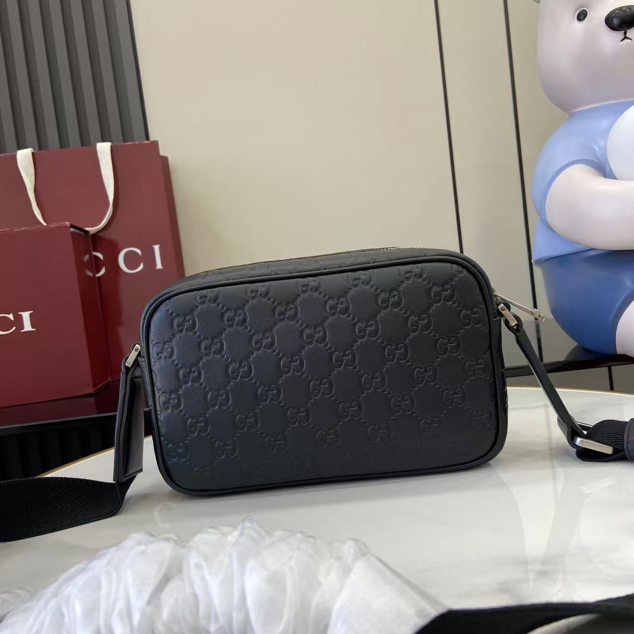 Gucci crossbody bag, dark blue embossed GG pattern, rounded shape with top zipper