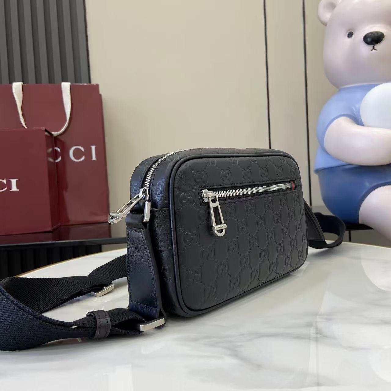 Gucci crossbody bag in dark blue with embossed GG pattern, silver zipper and strap