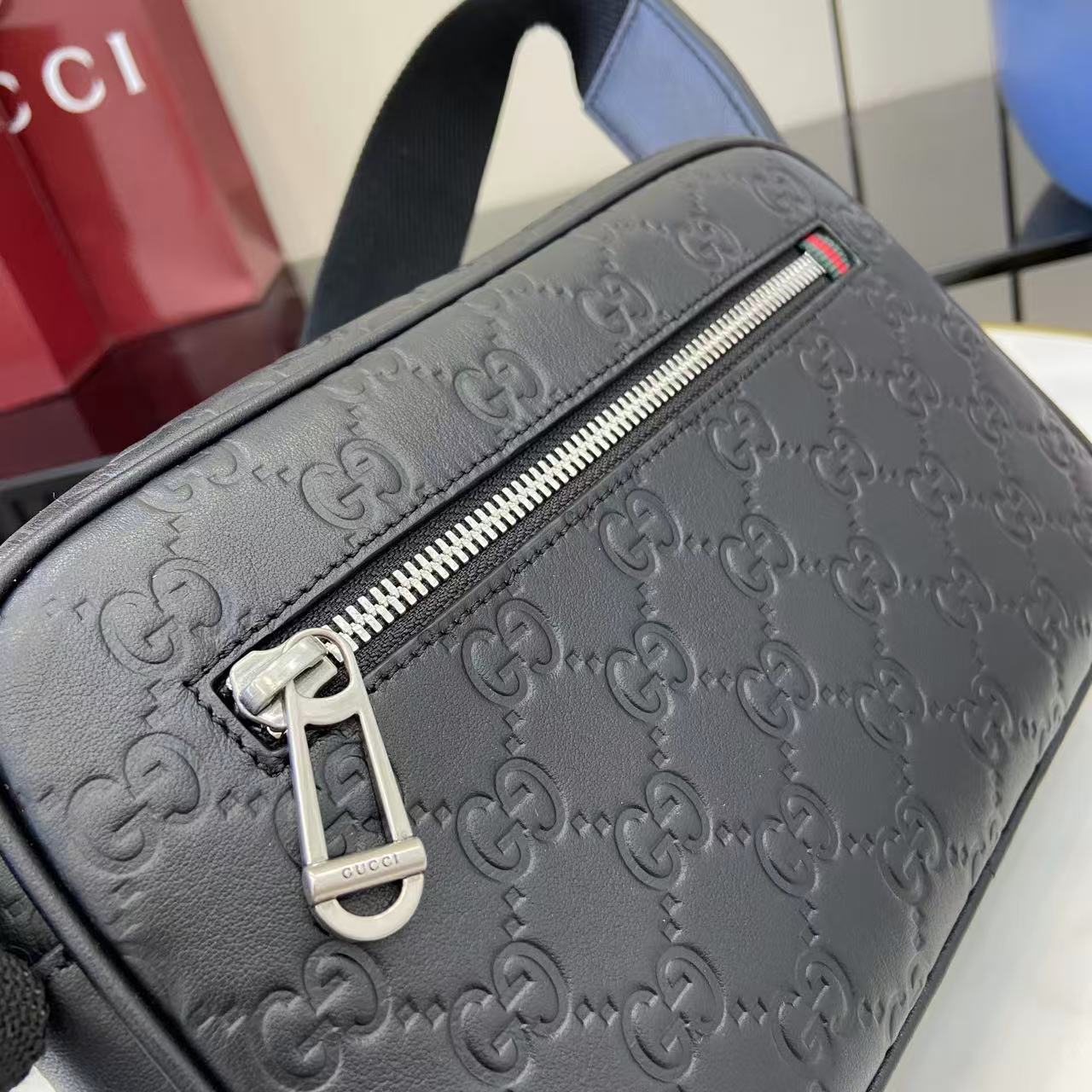 Gucci bag close-up: dark blue embossed leather with silver zipper pull and stripe accent