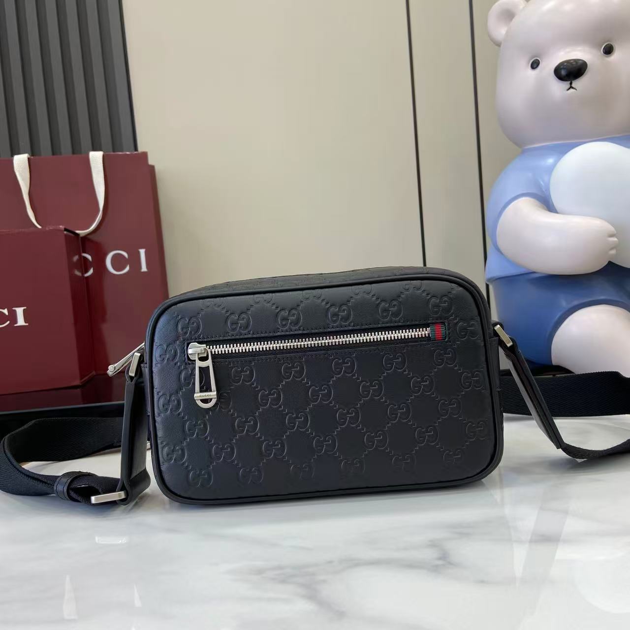 Gucci crossbody bag in dark blue with embossed GG pattern and front zip pocket