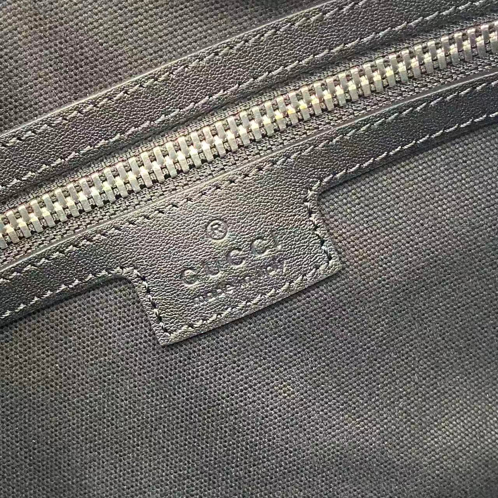 Gucci bag close-up of embossed leather label with stitching under the zipper