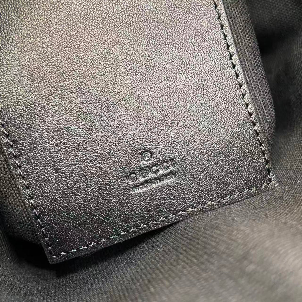 Gucci leather patch with 'GUCCI' logo, stitched edge on bag interior