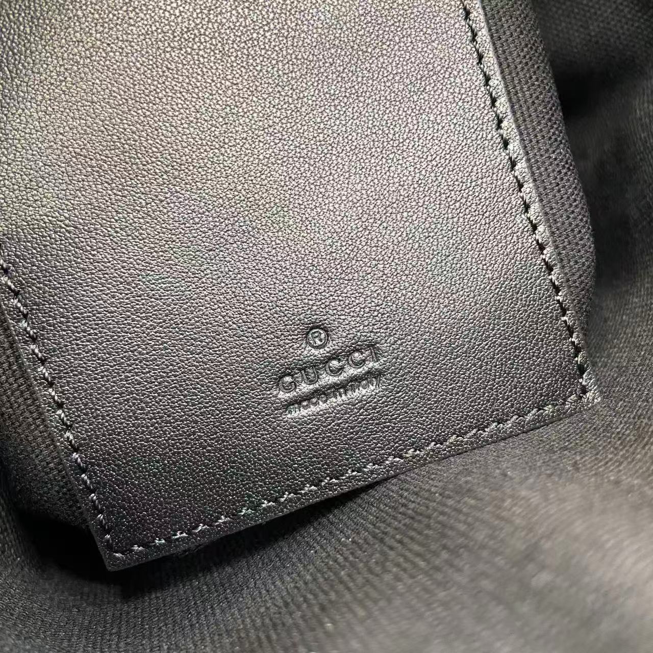 Gucci leather patch with 'GUCCI' logo, stitched edge on bag interior