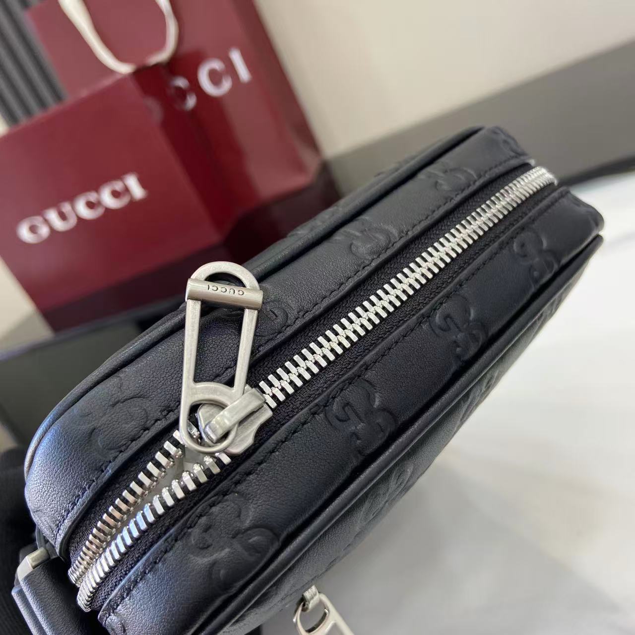 Gucci crossbody bag side view, silver zipper pull and embossed monogram trim