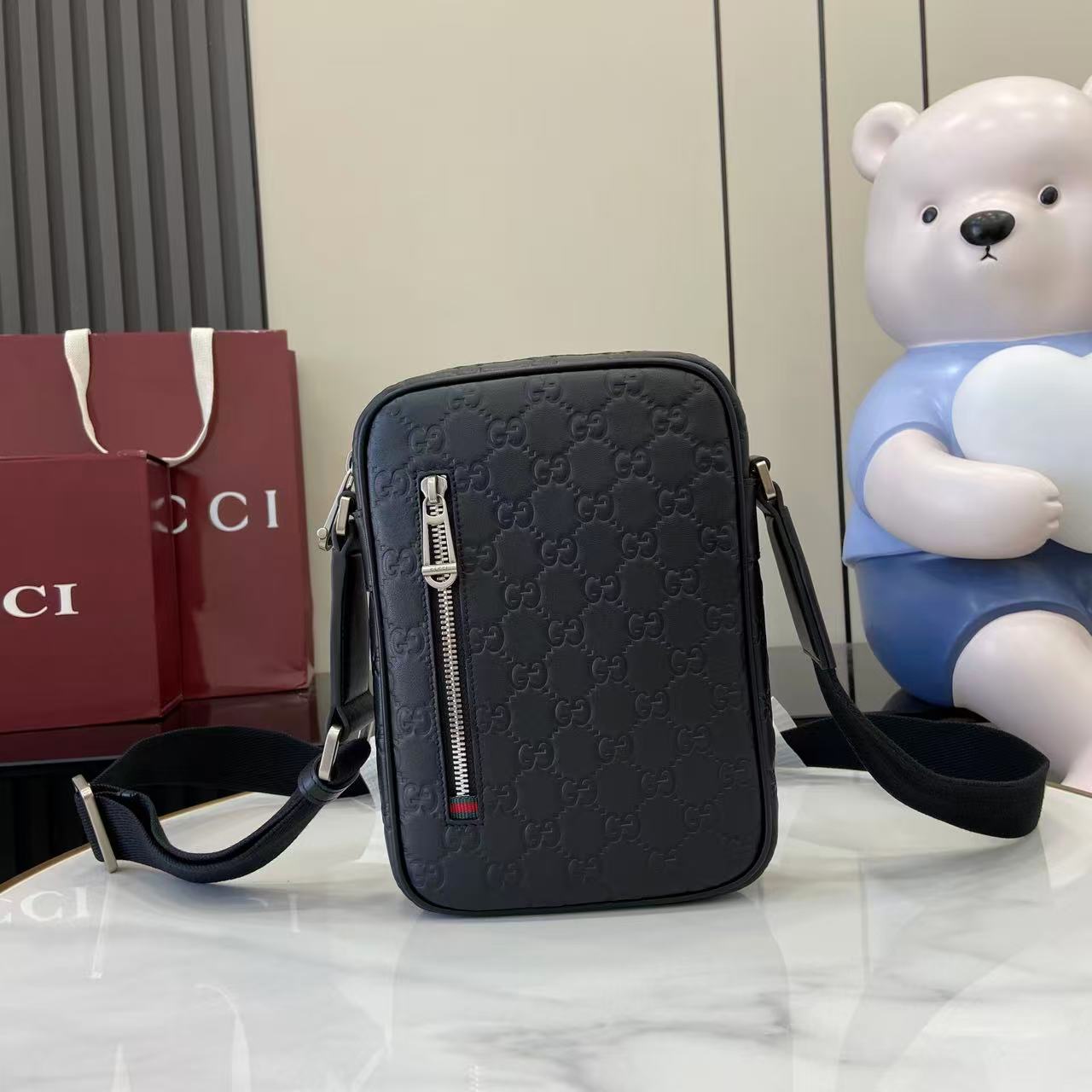 Gucci crossbody bag, embossed monogram pattern, front zip and adjustable strap