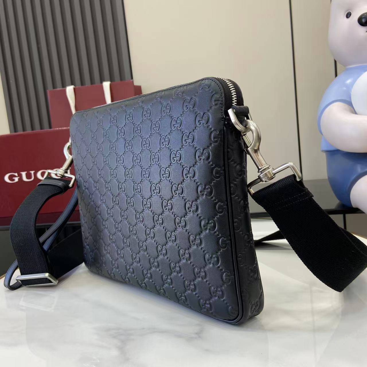 Dark navy GG monogram crossbody bag with zip top and adjustable shoulder strap