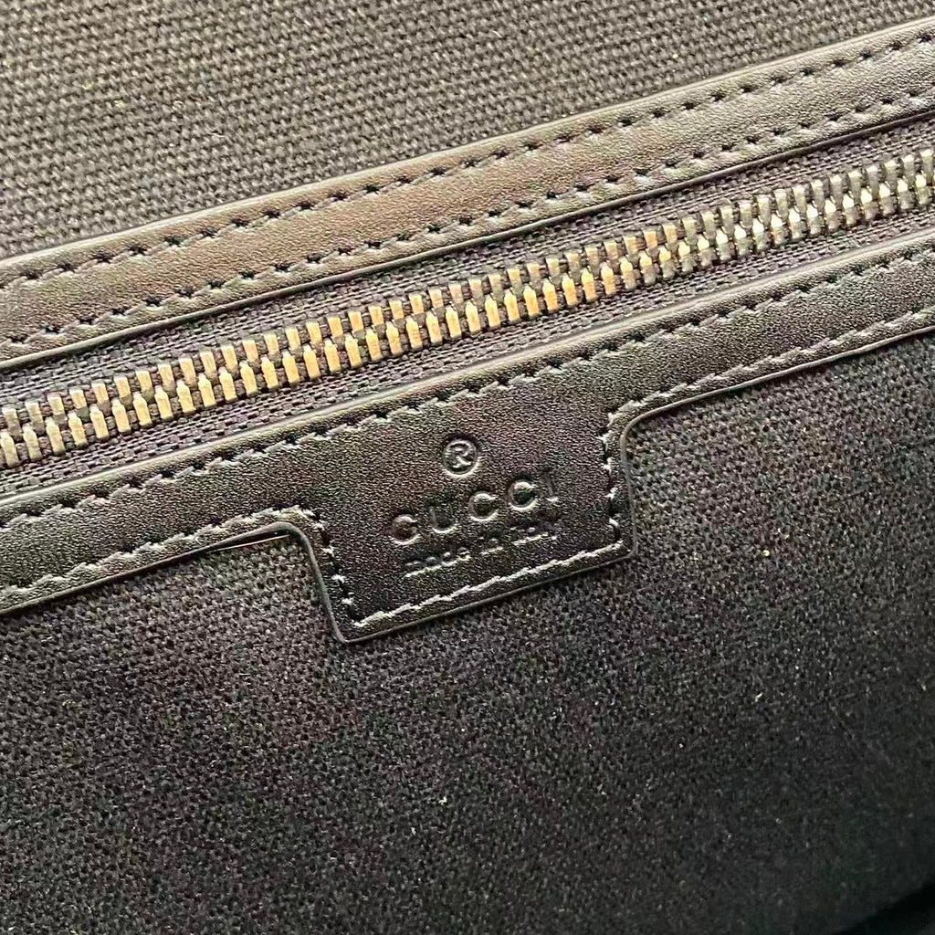 Blue embossed GG bag close-up of leather logo patch and zipper trim