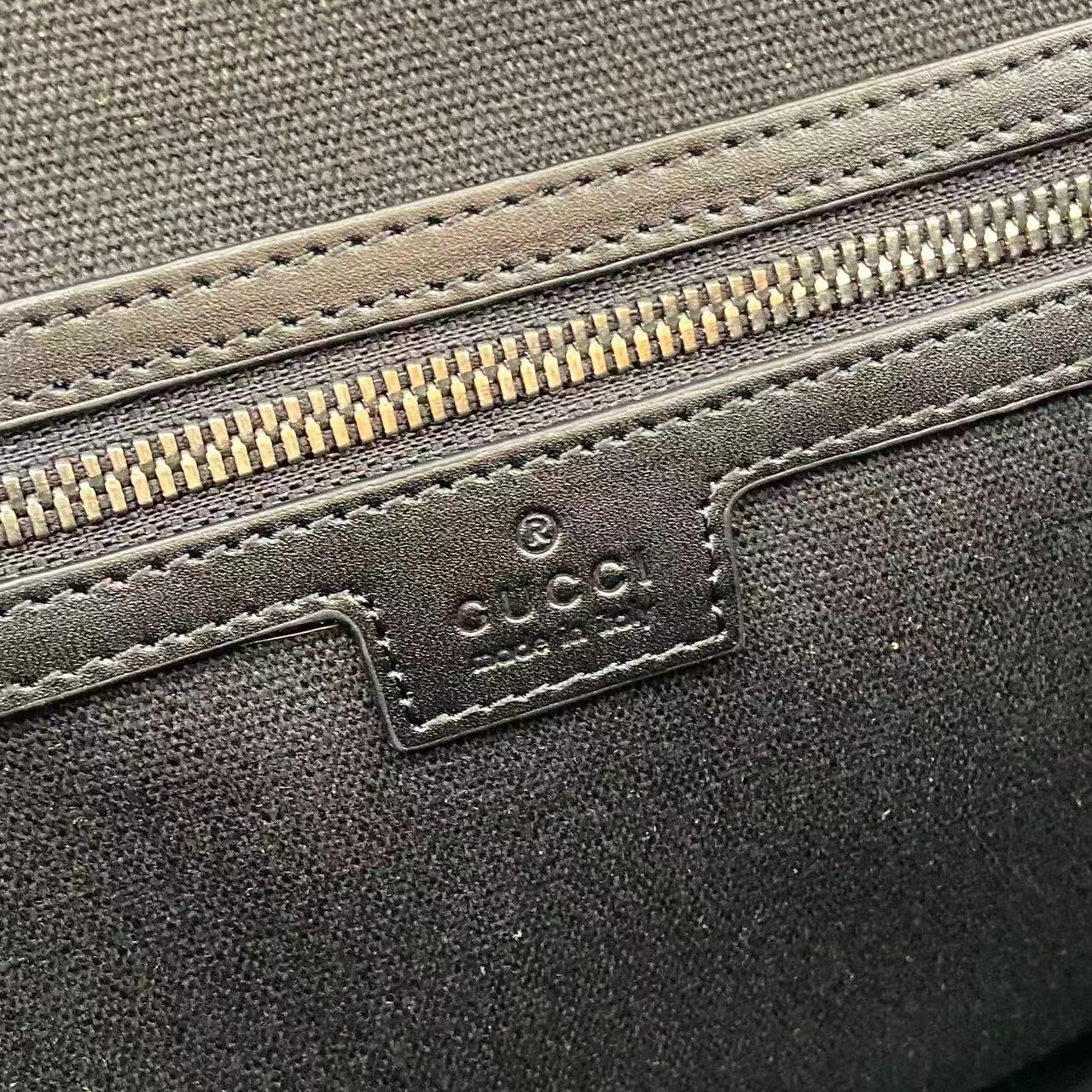 Blue embossed GG bag close-up of leather logo patch and zipper trim