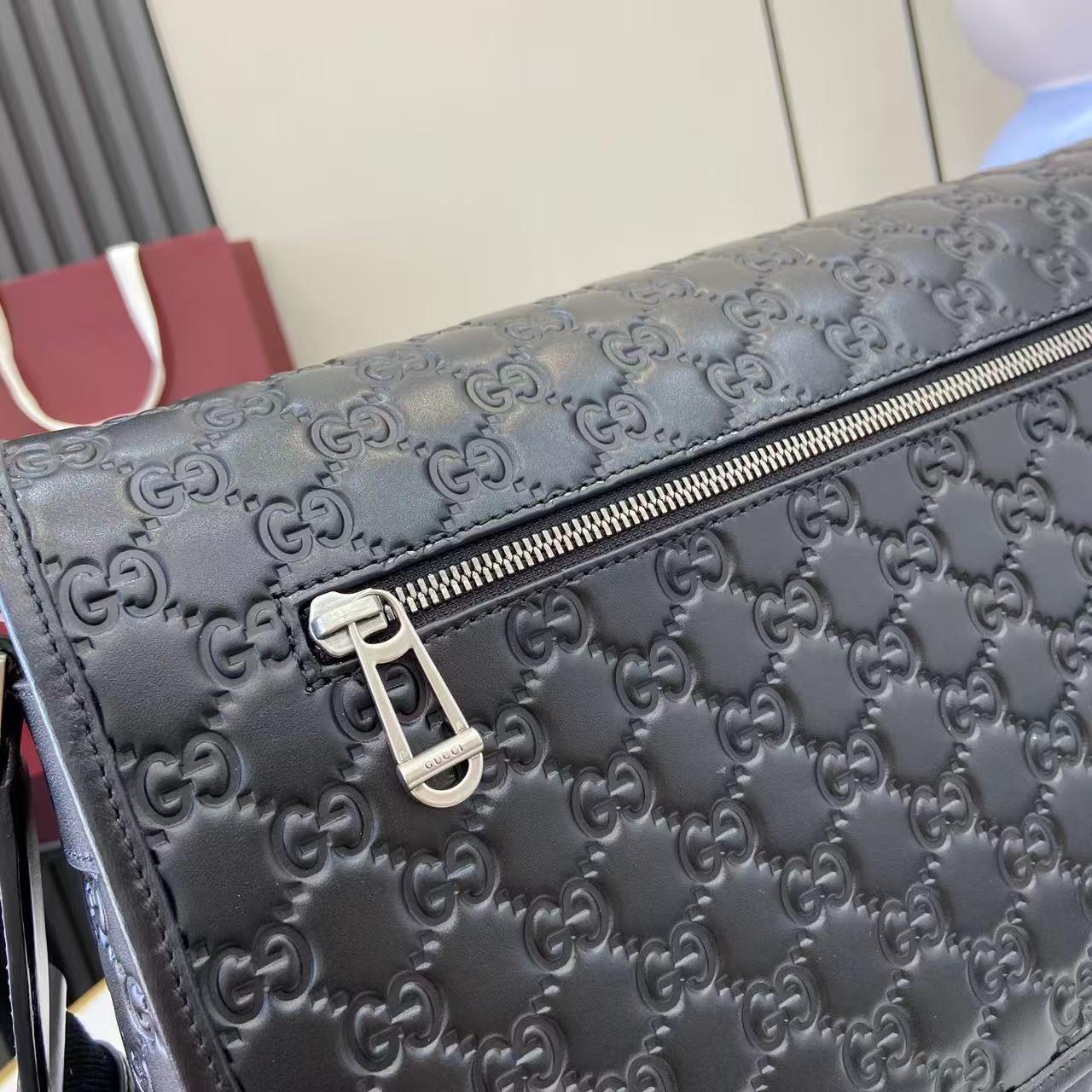 Blue embossed GG crossbody bag close-up of front zipper and logo hardware
