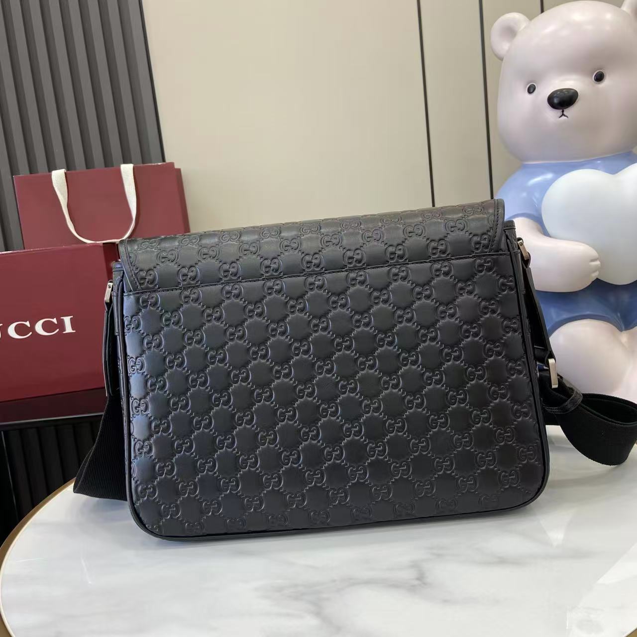 Blue embossed GG crossbody bag with curved flap and front zip closure