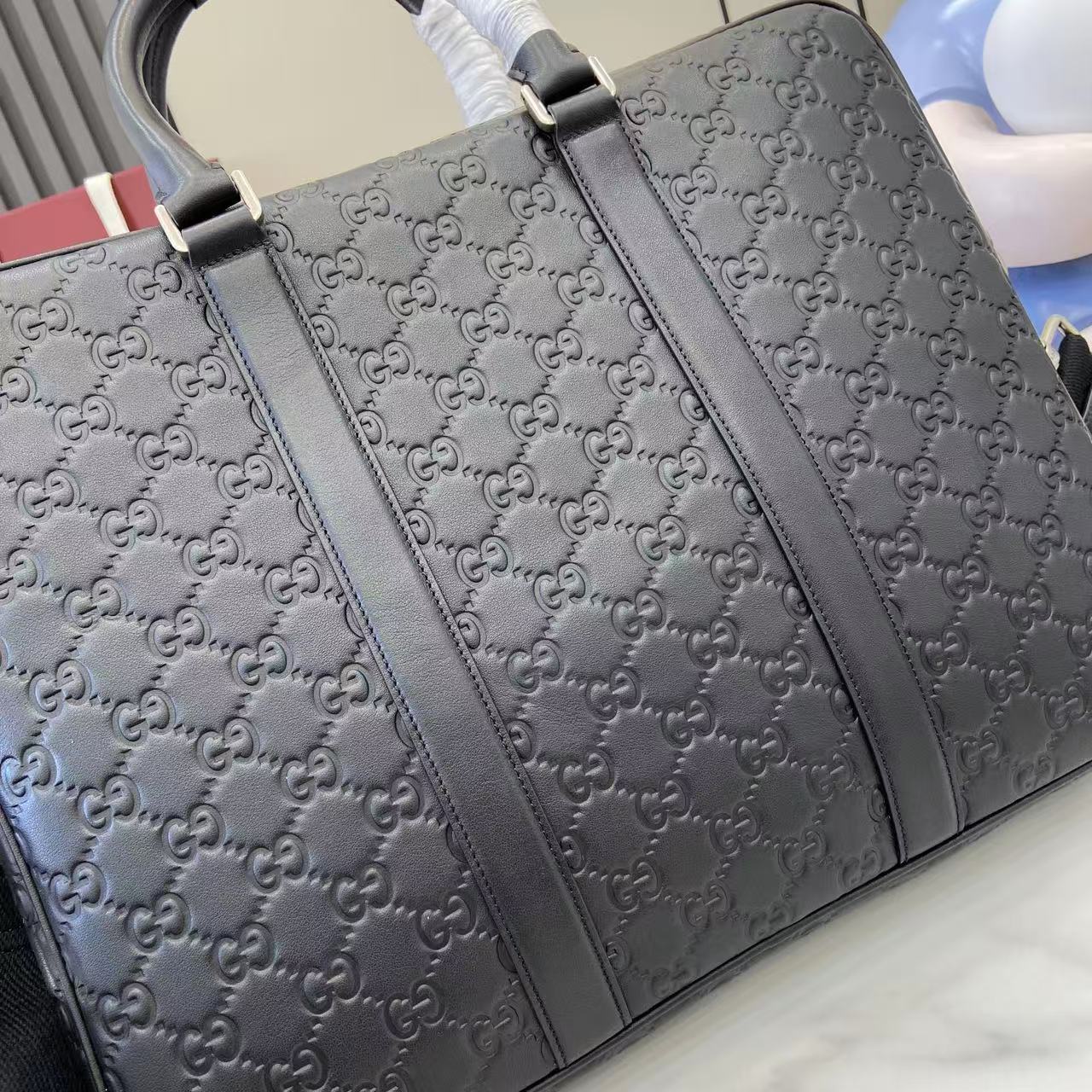 Gucci bag with embossed GG pattern and black leather handles