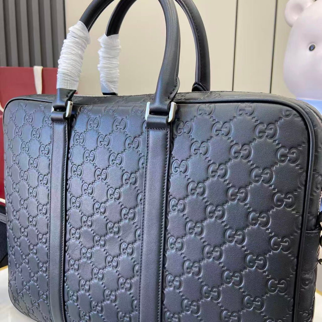 Gucci handbag close-up: navy GG monogram with front strap and top handles
