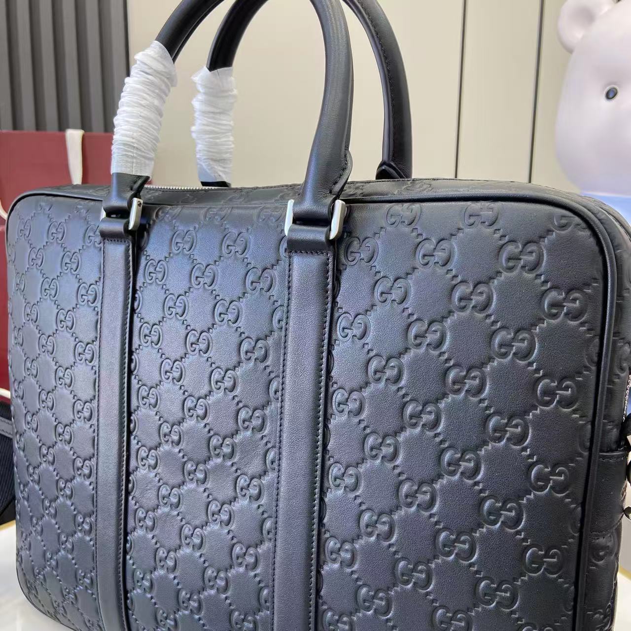 Gucci handbag close-up: navy GG monogram with front strap and top handles