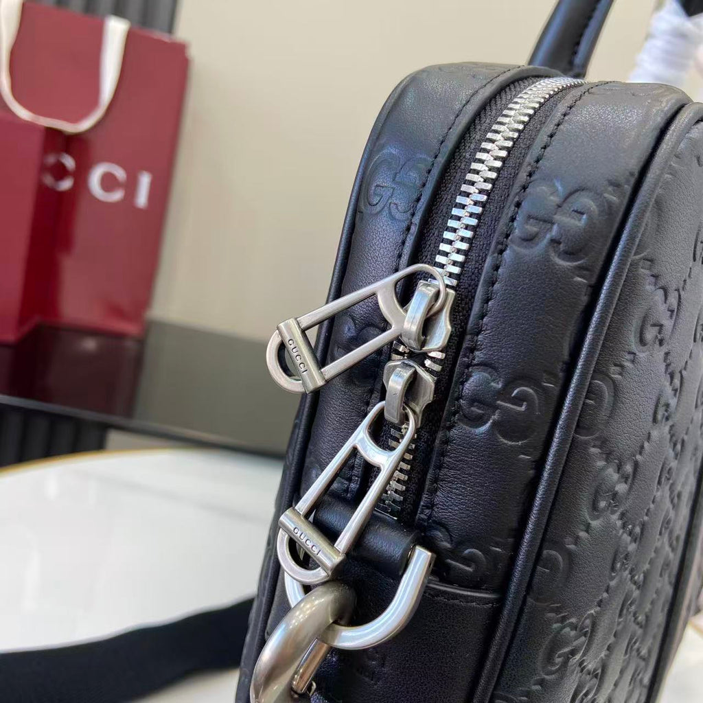 Gucci handbag close-up with silver hardware, navy GG monogram and zipper details