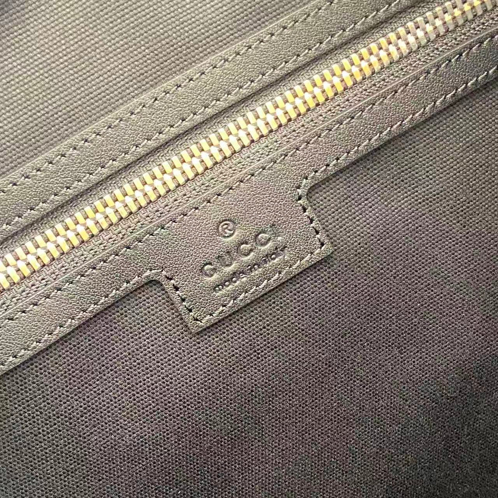 Gucci handbag close-up: navy fabric, gold zipper, embossed label patch