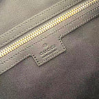 Gucci handbag close-up: navy fabric, gold zipper, embossed label patch