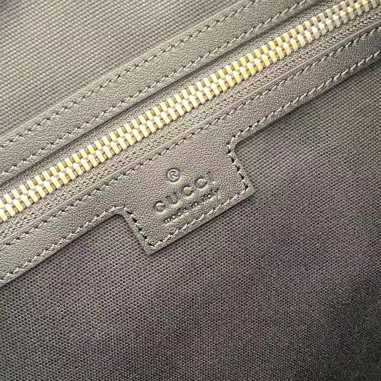 Gucci handbag close-up: navy fabric, gold zipper, embossed label patch