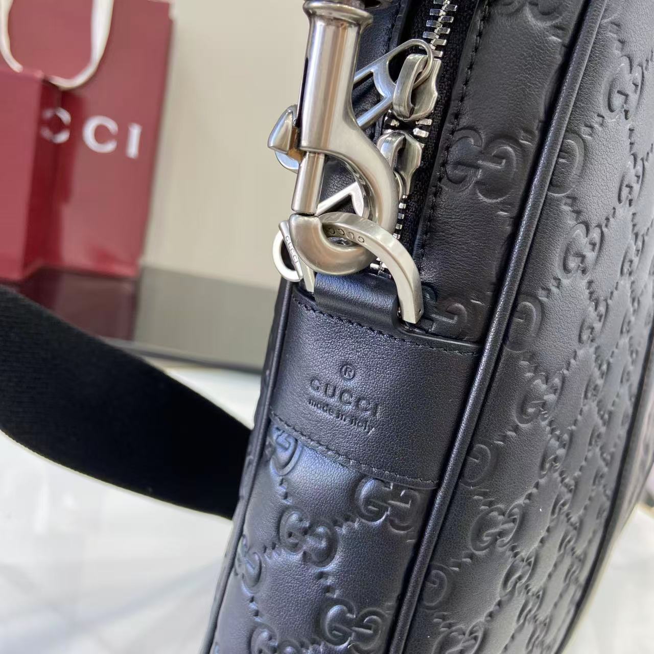 Gucci handbag hardware detail: navy strap with silver snap and embossed GG