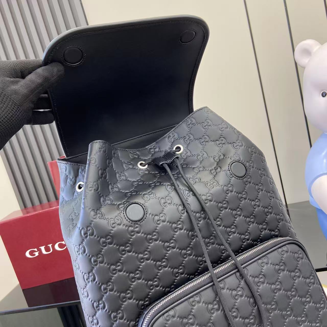 Gucci bag drawstring backpack front with embossed GG pattern and silver-tone hardware, light blue-gray