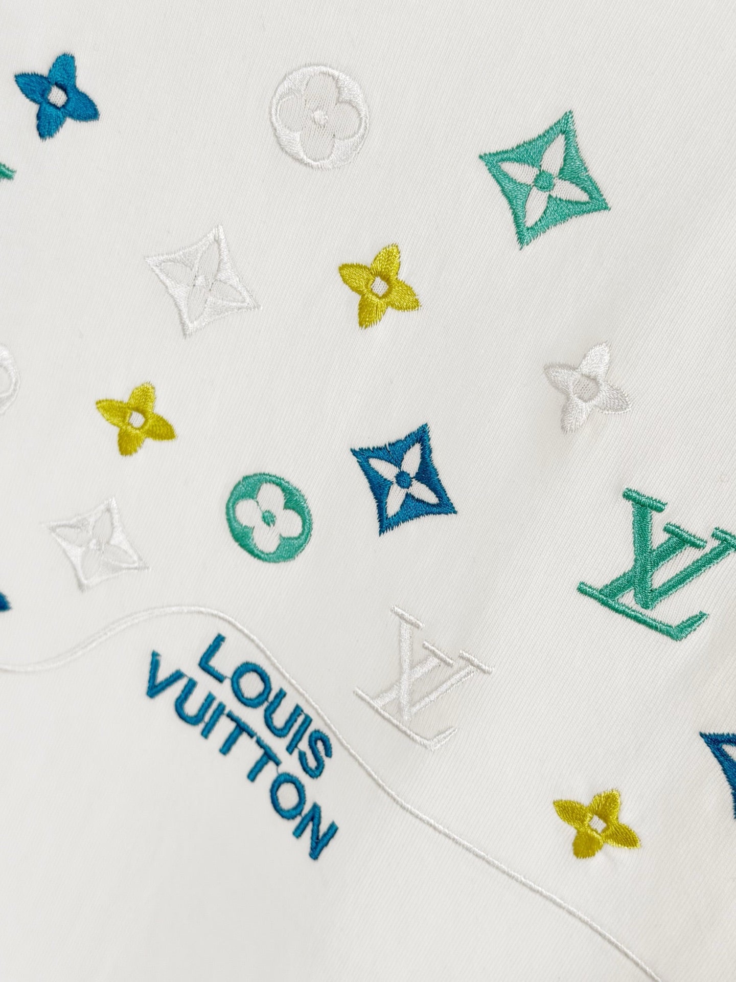 Louis Vuitton white T-shirt closeup with small multicolor monogram icons
