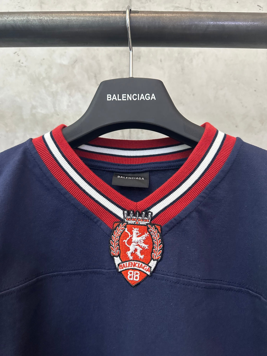 Balenciaga navy sweatshirt with red crest at V-neck and striped ribbed collar