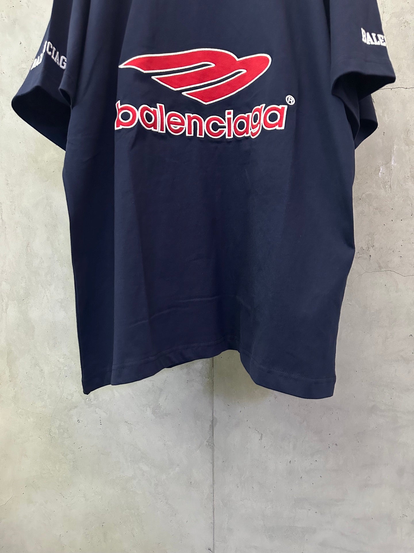Navy short-sleeve polo shirt with large red Balenciaga logo centered on front