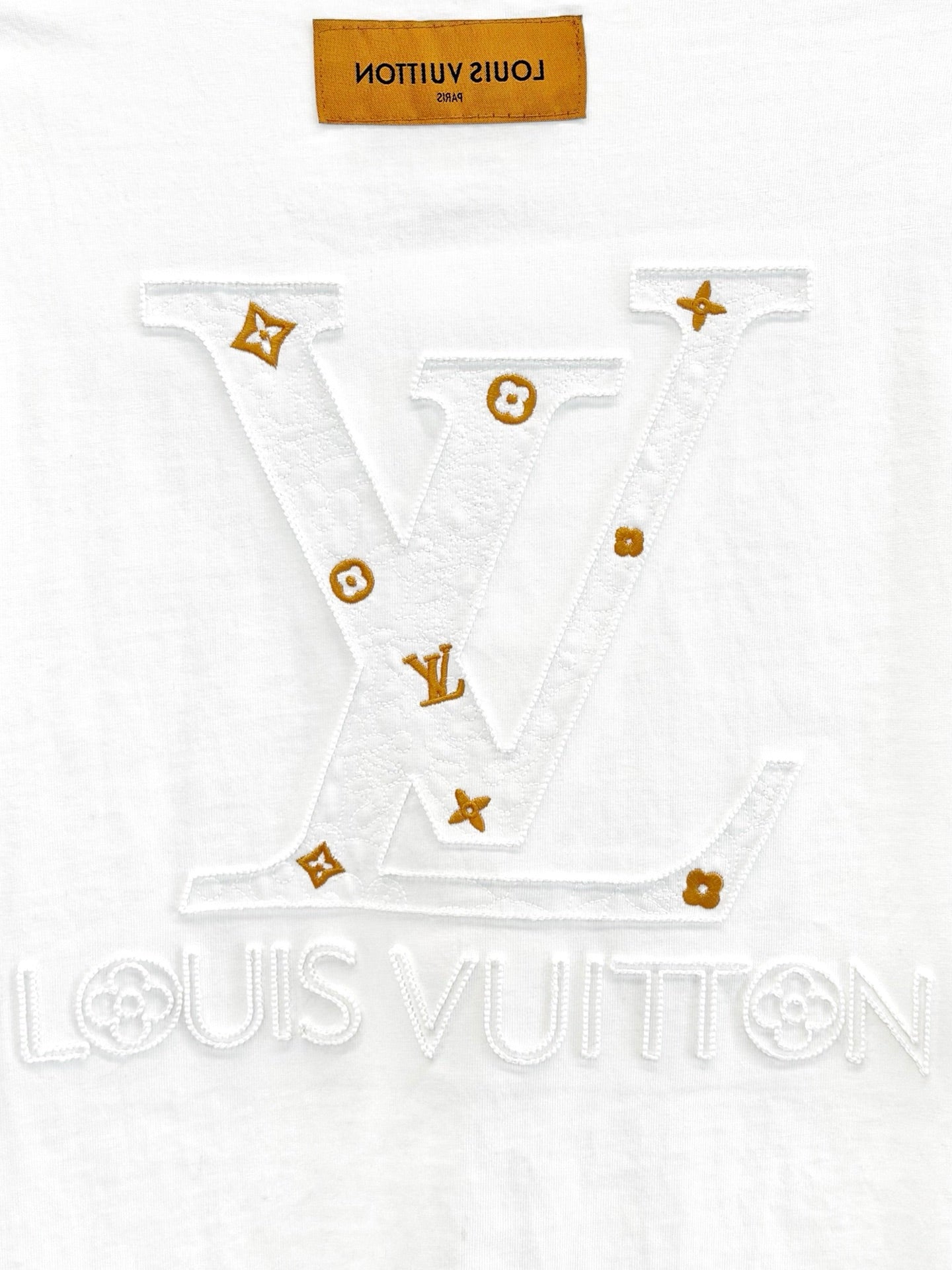 White T-shirt with large V-shaped embroidered logo and small gold motifs