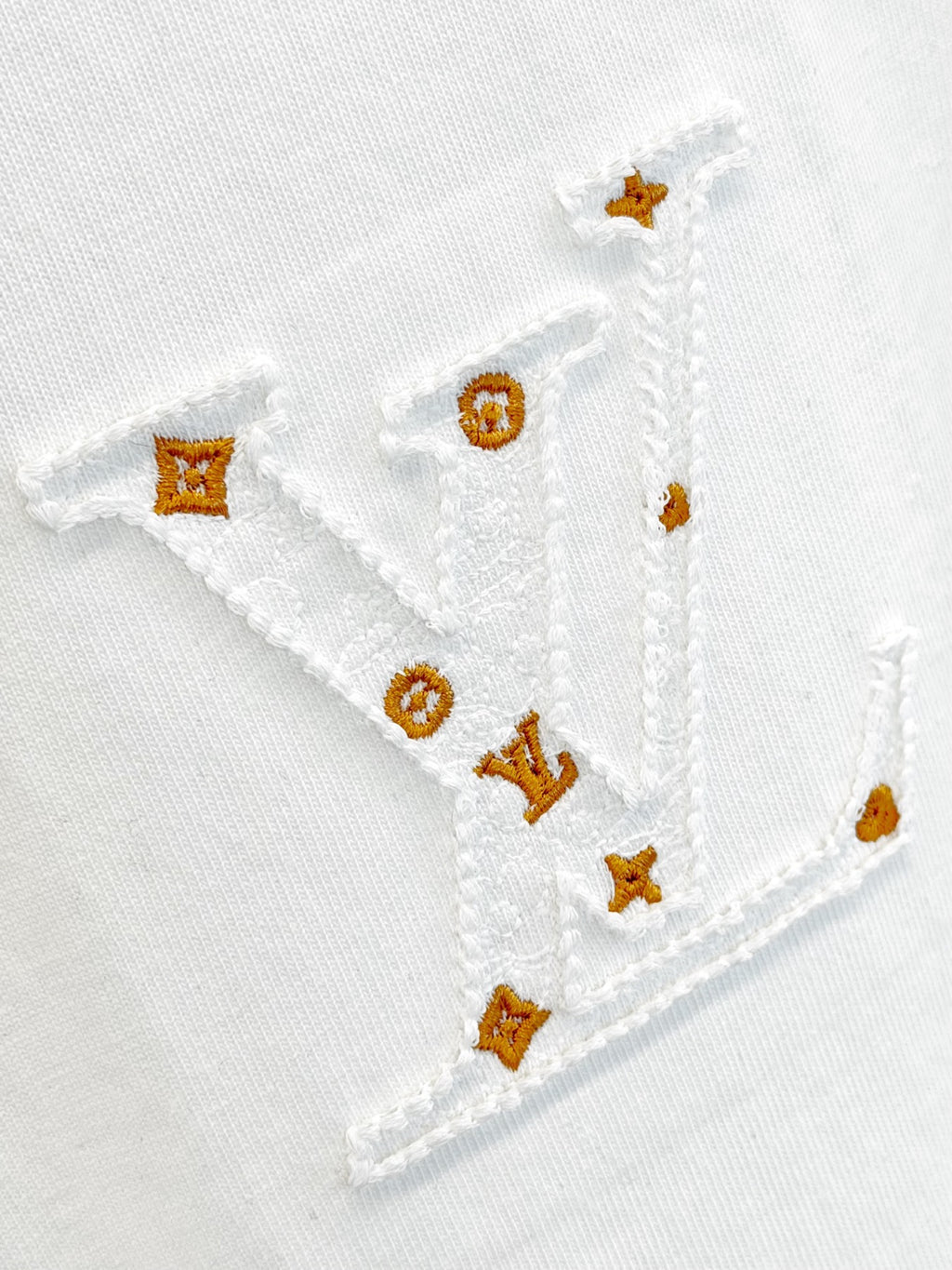 White T-shirt embroidery with gold and orange motifs stitched on the fabric