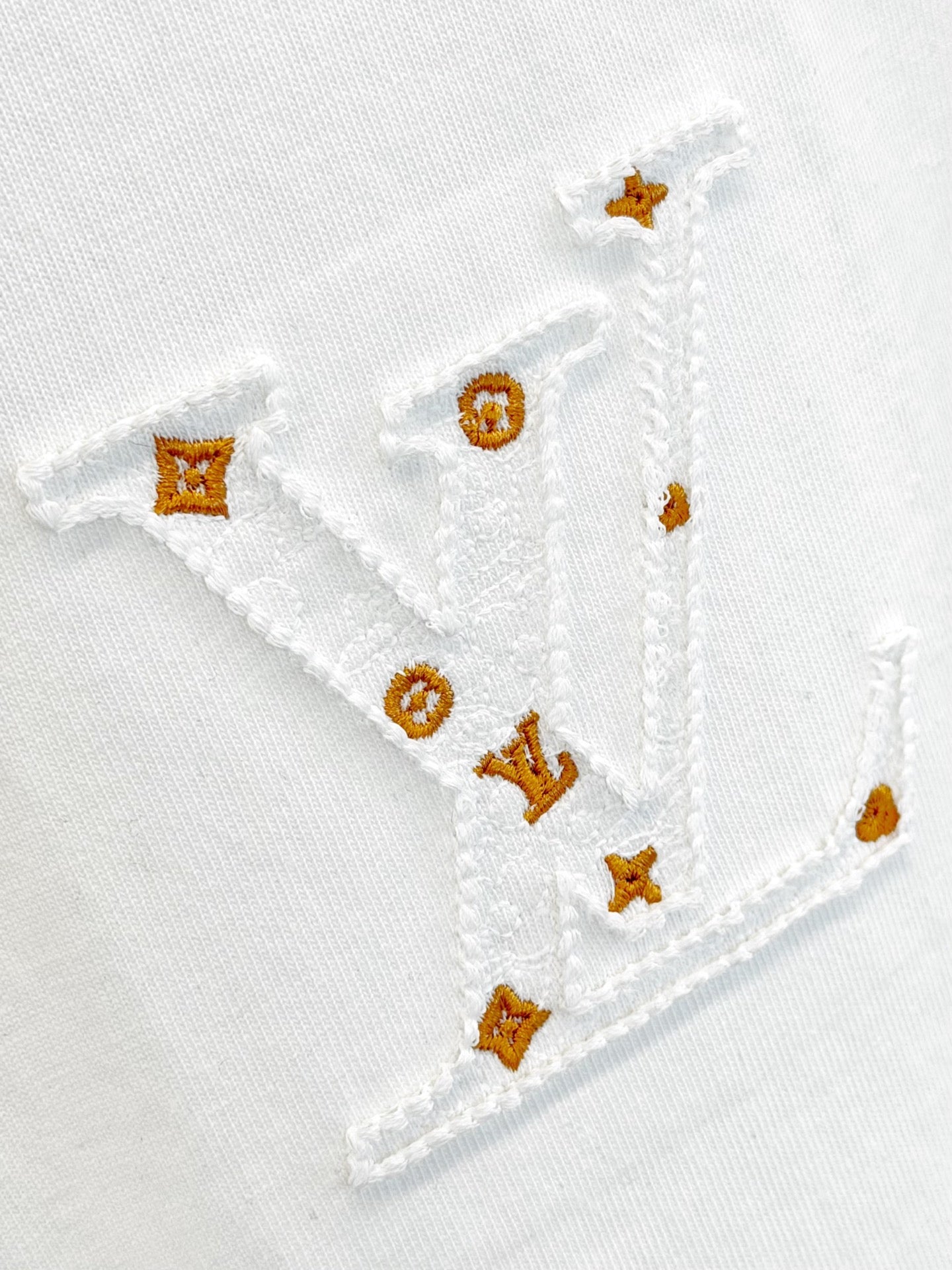 White T-shirt embroidery with gold and orange motifs stitched on the fabric